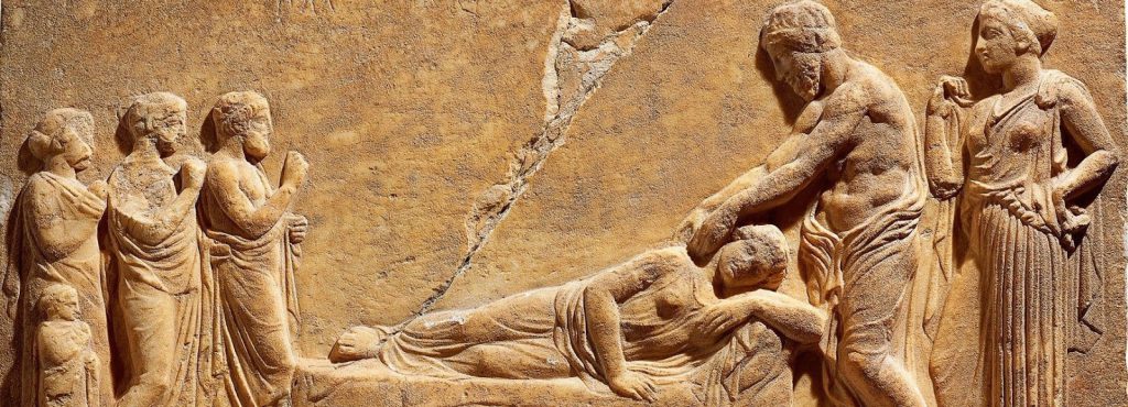 Bassorilievo greco che mostra un terapeuta mentre compie trattamenti vibrazionali, branca del Metodo Vibrazionale. Alla sinistra tre persone che osservano e alla destra una donna che assiste il terapeuta.
