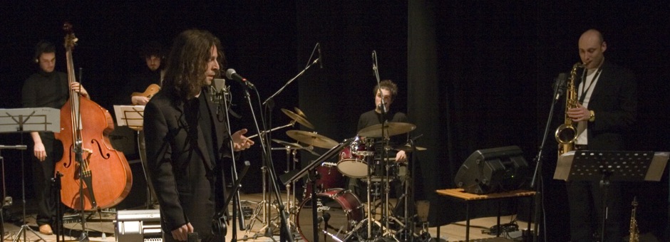 un sestetto jazz durante un concerto. In primo piano il cantante mentre esegue un canto jazz. Canto e aromonia jazz. In aria project: Manolo Rivaroli alla voce, Pedro Spallati al sassofono, Matteo Marcucci alla chitarra, Filippo Fanò al piano, Igor Spallati al contrabbasso, Alessandro Paternesi alla batteria. Fonico Roberto Lioli.