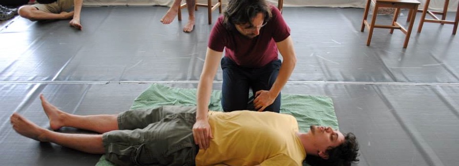 Il terapeuta sta toccando la cresta iliaca del paziente. Nell'educazione e rieducazione vocale è spesso necessario far distendere gli allievi a terra.